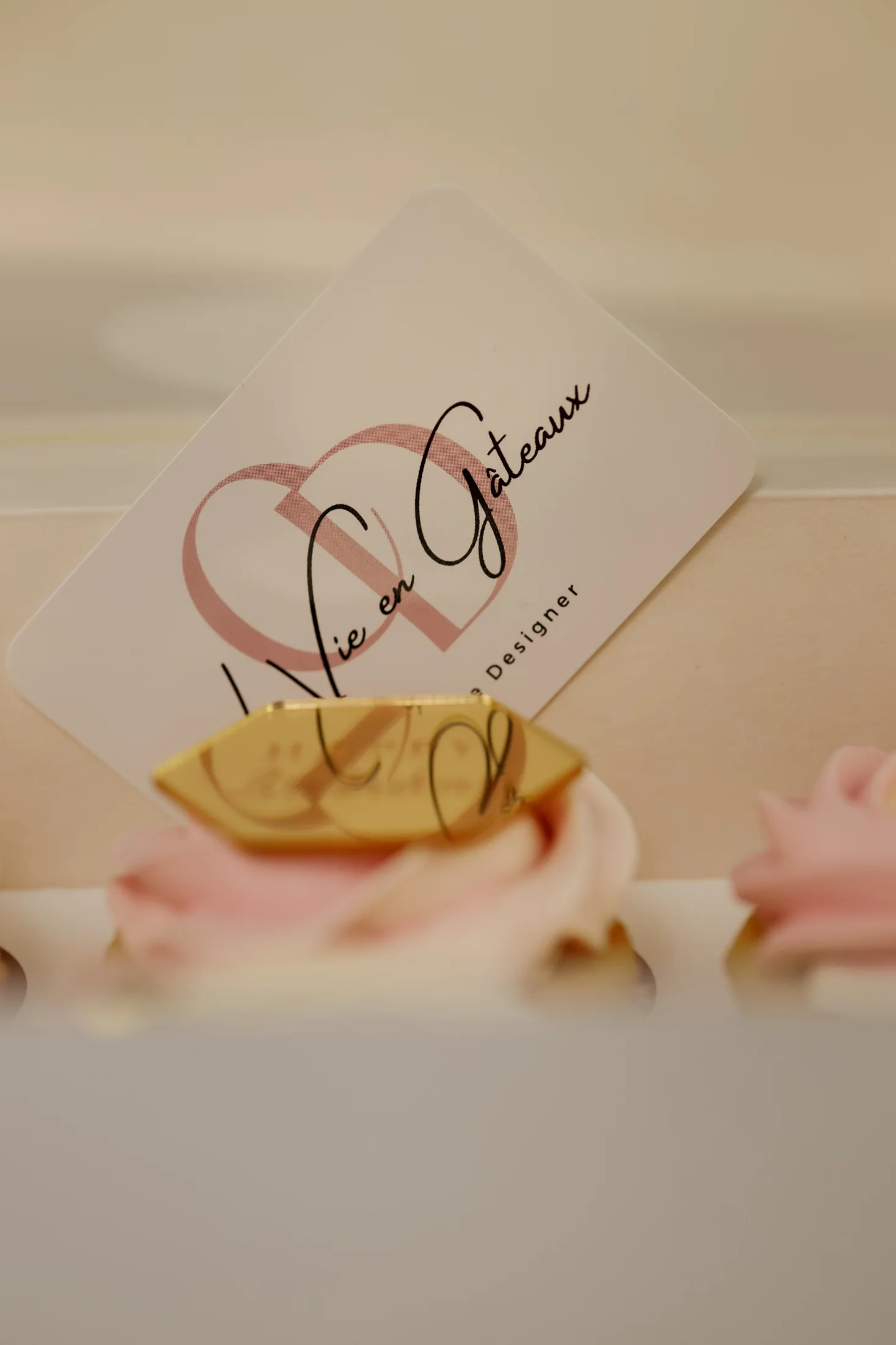 Carte de visite La Vie En Gâteaux avec l’ancien logo manuscrit, posée sur des cupcakes
